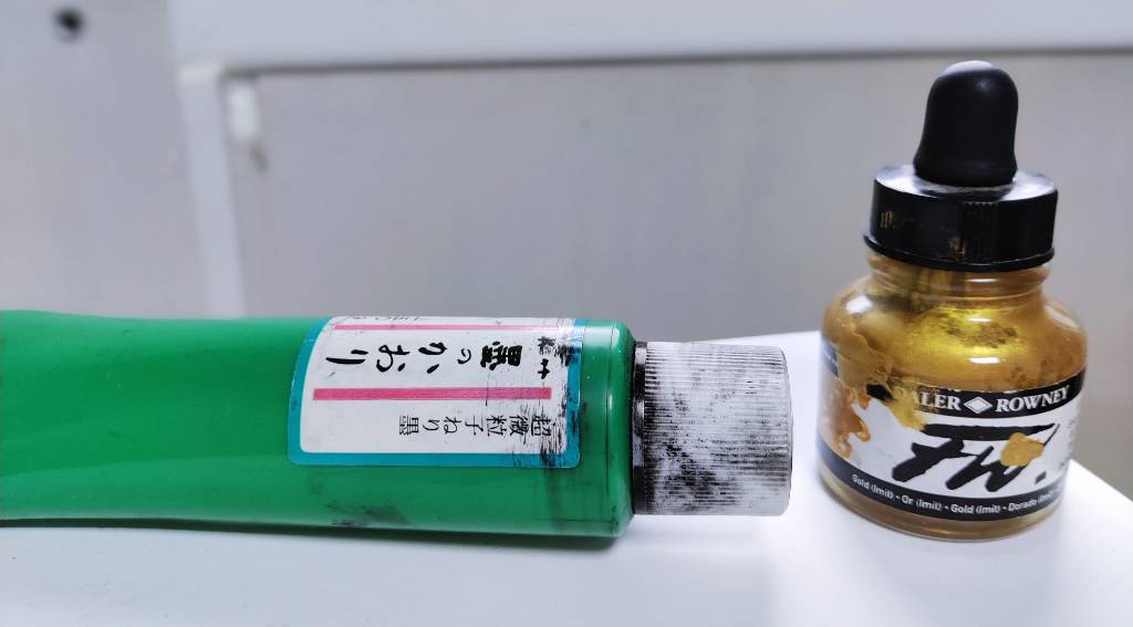 Un tube d'encre avec une étiquette en japonais et un flacon d'entre doré où on devine la marque Daler-Rowney