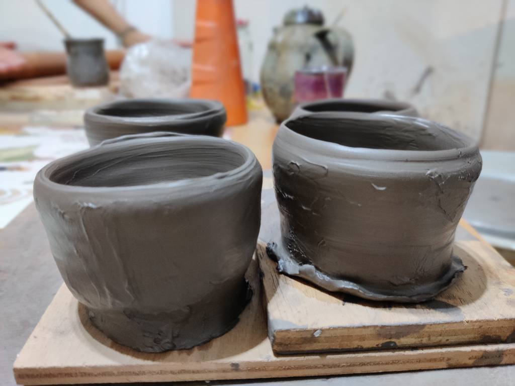 Quatre petits pots en terre à l'état d'ébauche (le pot est formé mais il y a plein de défauts de surface et le pied est encore un gros pâté.