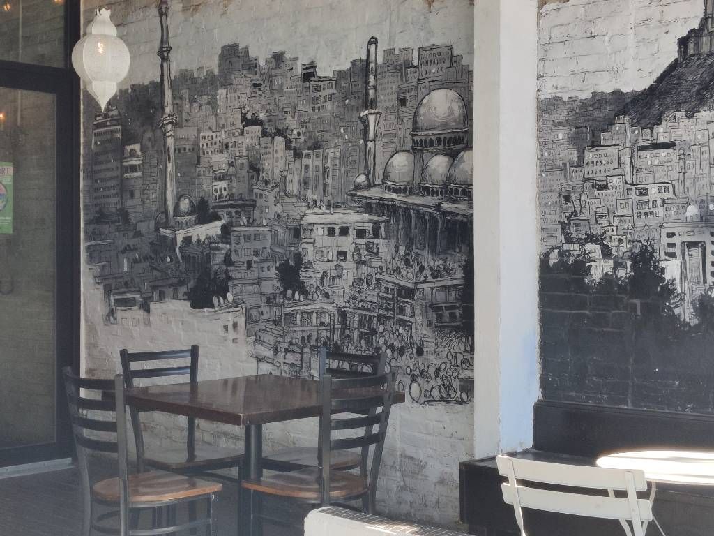 Graffiti sur le mur d'une terrasse de café couverte représentant une ville