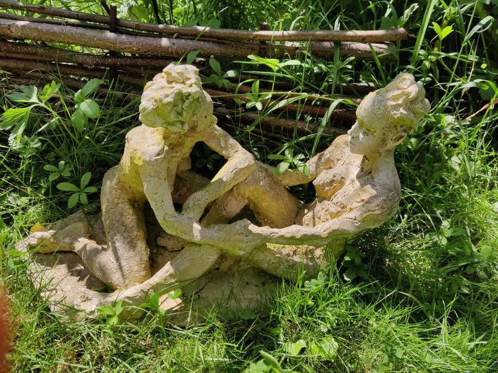 Une sculpture représentant deux personnes en discussion, posée dans l'herbe