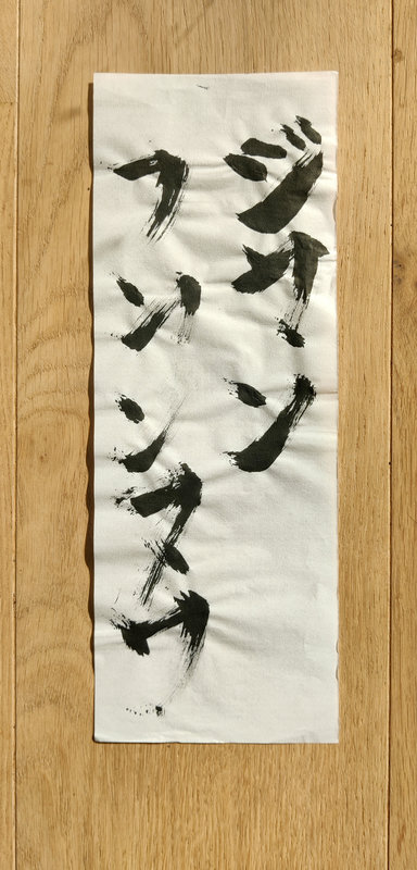 Sur un papier de calligraphie japonaise qui a un peu gondolé, traces d'encre noires faisant, normalement, penser à du japonais